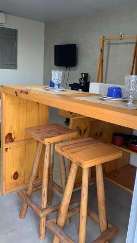 uma mesa de madeira com dois bancos de madeira e uma mesa com um balcão em Chalé das flores lírio em São Miguel do Gostoso
