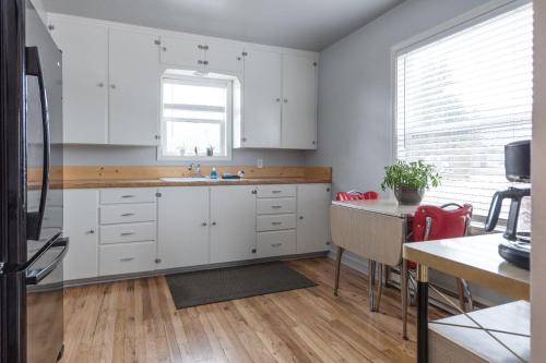 a kitchen with white cabinets and a sink and a table at Serendipity Cottage in Joseph
