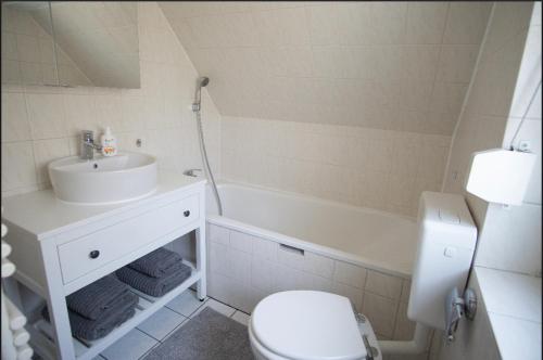 a bathroom with a sink and a toilet and a tub at Haus am See in Schwielowsee