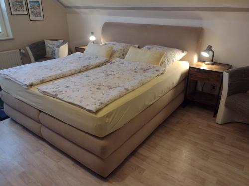 a large bed in a room with a chair and a table at Gästehaus AM HERMANN in Hörstel