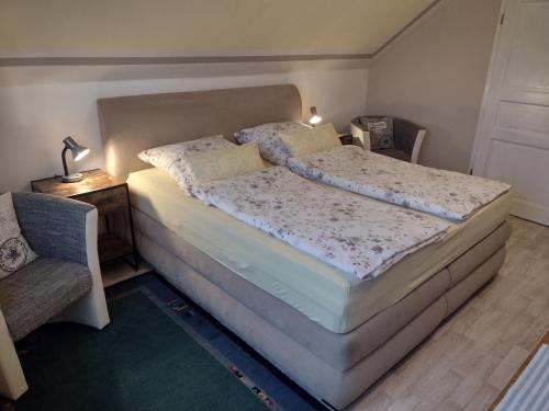 ein Bett in einem Schlafzimmer mit einer Lampe und einem Stuhl in der Unterkunft Gästehaus AM HERMANN in Hörstel