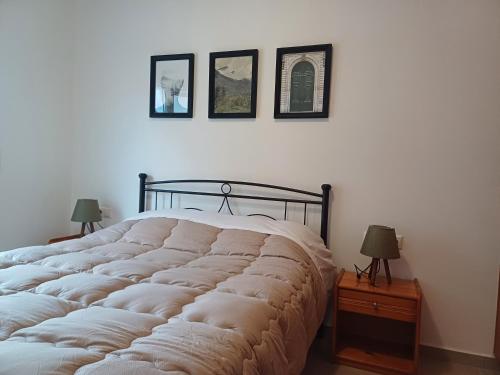 a large bed in a bedroom with three pictures on the wall at Comfy and Izzy apartment in Karlovasi