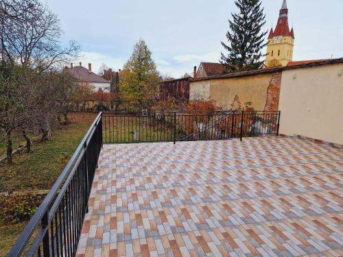a brick walkway with a fence and a church at Studio minunat de vacanta Cristian in Cristian