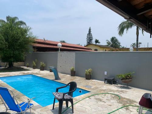 a swimming pool with two chairs next to a house at Casa para alugar em Bertioga - Piscina, Wifi e Churrasqueira in Bertioga