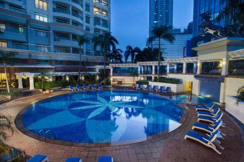 a large swimming pool with lounge chairs and a building at Somerset Grand Citra Jakarta in Jakarta