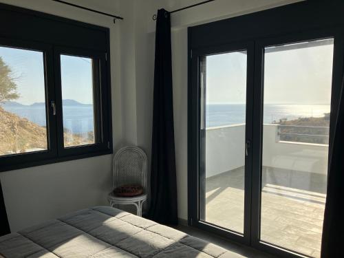 a bedroom with two windows and a bed and a balcony at Anifora Seaview Villa in Agios Pavlos