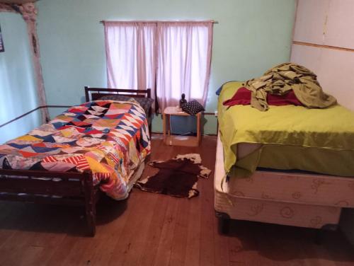 1 dormitorio con 2 camas y suelo de madera en Malegus en Epuyén