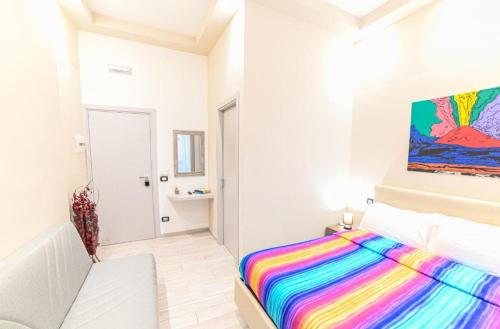 Residenza Suarez في نابولي: غرفة نوم بيضاء مع سرير ملون ولوحة على الحائط