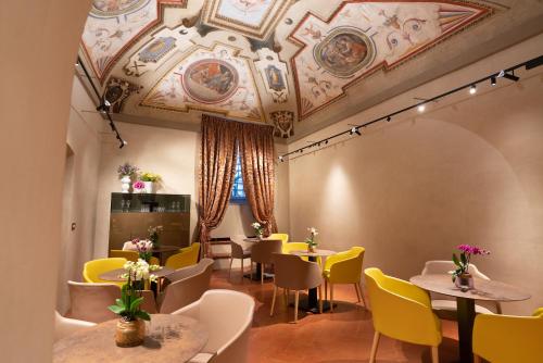 ein Esszimmer mit Tischen und gelben Stühlen in der Unterkunft Palazzo Mosela Alla Porta in Montepulciano
