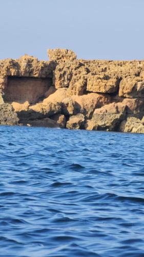 um corpo de água ao lado de um penhasco rochoso em maison damour el haouaria chez h & h em El Haouaria