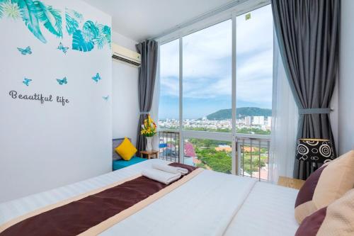une chambre avec un lit et une grande fenêtre dans l'établissement The Grand Condotel, à Vung Tau