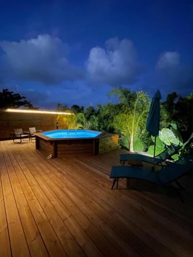 a deck with a pool and two chairs and an umbrella at La Papaye d’Or in Saint-François