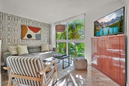a living room with a couch and a tv at Treetop Retreat! Cozy 2 Bedroom In Heart Of Grove in Miami