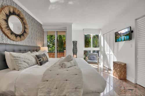 a bedroom with a large white bed with a mirror at Treetop Retreat! Cozy 2 Bedroom In Heart Of Grove in Miami