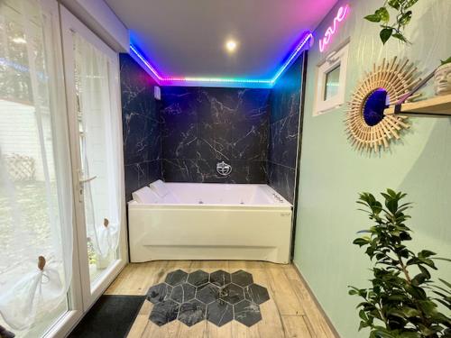 een badkamer met een wit bad met paars licht bij Les nids de la Baie in Favières
