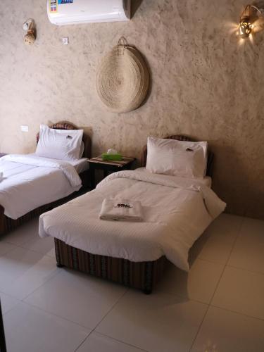 a room with two beds with white sheets at Canyon Rest House Jabal Shams in Al Ḩamrāʼ