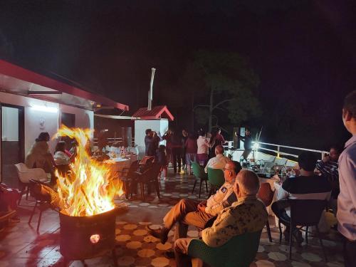 a group of people sitting around a fire pit at Hotel Le Halcyon Kasauli in Solan