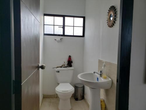 a white bathroom with a toilet and a sink at Casita del páramo Sarmora in La Calera