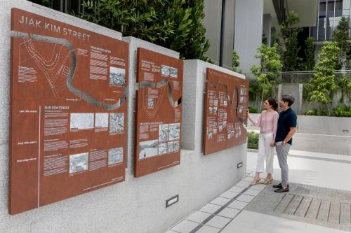 two people standing next to a wall with signs at Fraser Residence River Promenade, Singapore in Singapore
