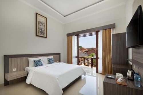 a bedroom with a bed and a television and a balcony at Jineswari Kuta by Kamara in Kuta