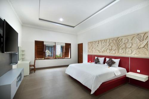 Jineswari Kuta by Kamara في كوتا: غرفة نوم بسرير كبير وتلفزيون بشاشة مسطحة