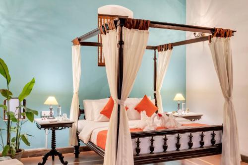 a bedroom with a canopy bed with orange pillows at Villa Sereno by Insignia Villas in Assagao