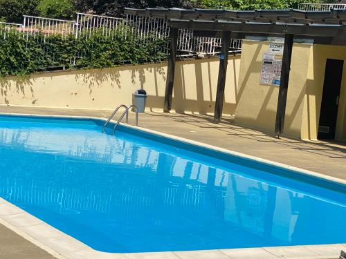 une piscine bleue avec une pergola à côté d'un bâtiment dans l'établissement Gîte au nid de l’écureuil, à Bœrsch