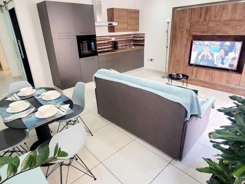 uma cozinha com um sofá, uma mesa e uma televisão em New&Cosy Apartment with Balcony em San Ġwann