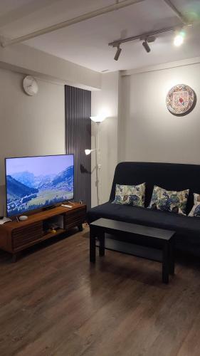 a living room with a couch and a flat screen tv at Papilukas Room Kalibata City - Studio Gold in Jakarta