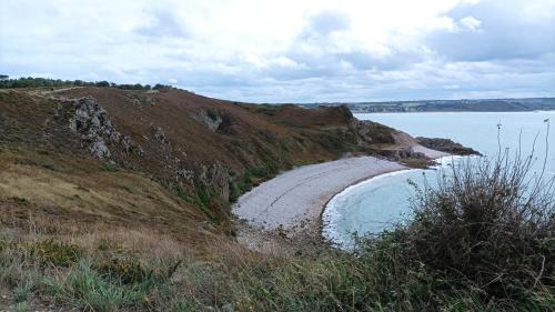a dirt hillside with a beach next to the water at ANCRE BLEU in Hillion