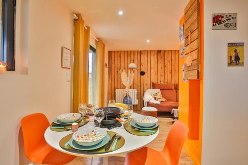 a dining room with a white table and orange chairs at CHALET VINTAGE - Les Belles Ouvrières in Clermont-Créans