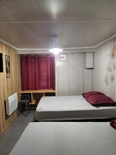 um quarto com 2 camas e uma cortina vermelha em STUDIO ENTRE PARIS et DISNEY 1 em Torcy