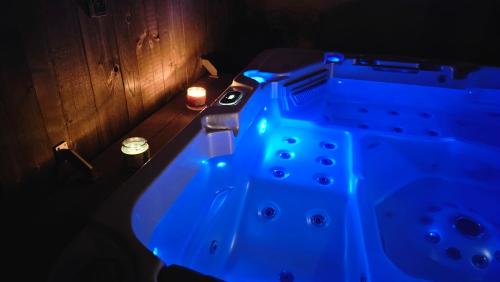 uma banheira com luzes azuis num quarto escuro em Jacuzzi privé à 30km d'Annecy em Desingy