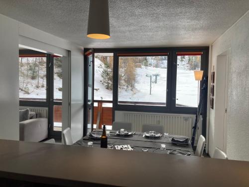 ein Esszimmer mit einem Tisch und einigen Fenstern in der Unterkunft Appartement 4 pièces - 8 personnes - Résidence le France in La Plagne Tarentaise