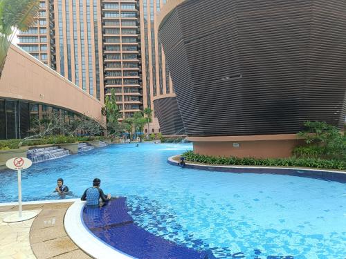 twee mensen zitten in een groot zwembad in een stad bij Times Square Apartment By Skyline in Kuala Lumpur