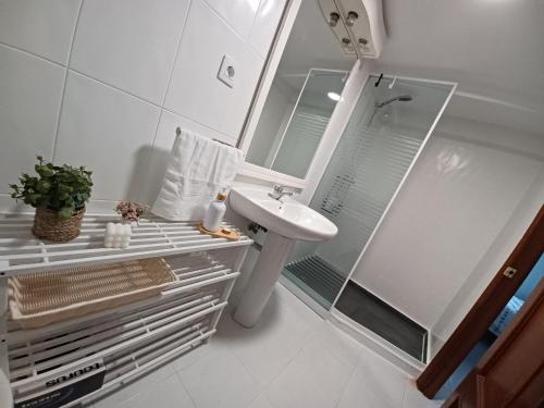 a white bathroom with a sink and a shower at Casa Montecelo in Paderne