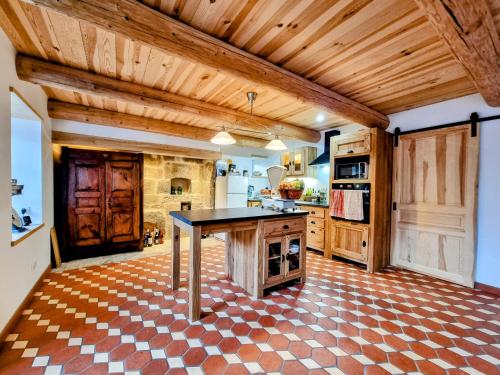 a large kitchen with wooden ceilings and a table at GITE LA MENOU in Usson-en-Forez