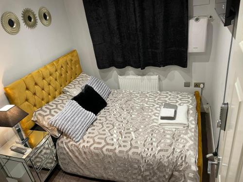 a small bedroom with a bed with a yellow headboard at Crestfield Lodge in Thamesmead