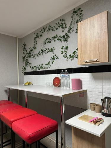 a kitchen with a counter with red stools in it at ArArAt-POZNYAKI Hostel KYIV in Kyiv