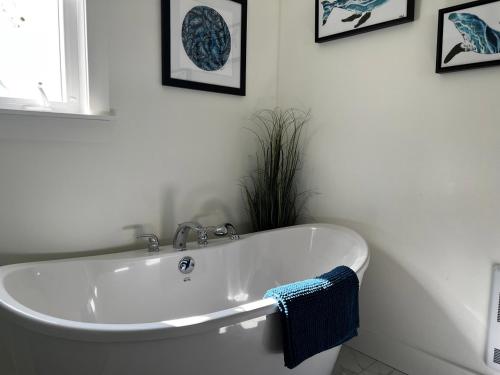 bañera blanca en el baño con fotos en la pared en Bambury's Hillside Chalets, en Rocky Harbour