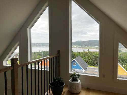 a staircase with three windows with a view of the water at Bambury's Hillside Chalets in Rocky Harbour