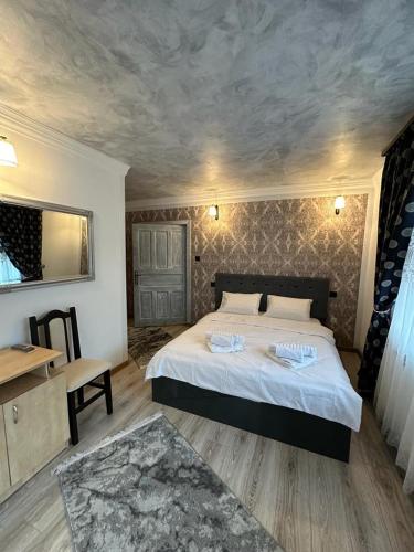 a bedroom with a large bed and a table and a desk at PENSIUNEA Mari Haus in Poiana Mărului