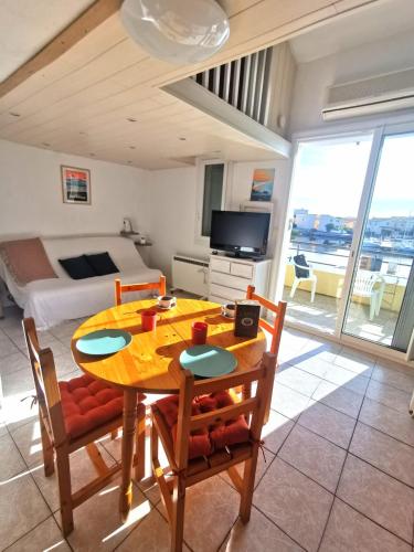 une salle à manger avec une table et des chaises et une chambre dans l'établissement Appartement coup de coeur les pieds dans l'eau, au Barcarès