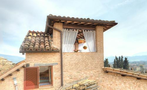 a building with a window with a white curtain at Spello House Altana in Spello
