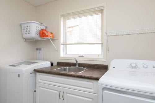 a white kitchen with a sink and a window at Elegant Place Near University of Manitoba in Winnipeg