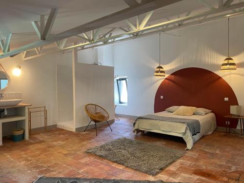 une chambre avec un grand lit et une chaise dans l'établissement Grande Maison de Maitre contemporaine à 10 min de la mer et Piscine, à Salles-d'Aude