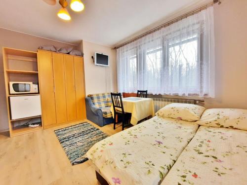 ザコパネにあるWynajem Pokoi Zakopaneのベッドルーム1室(ベッド2台、テーブル、窓付)