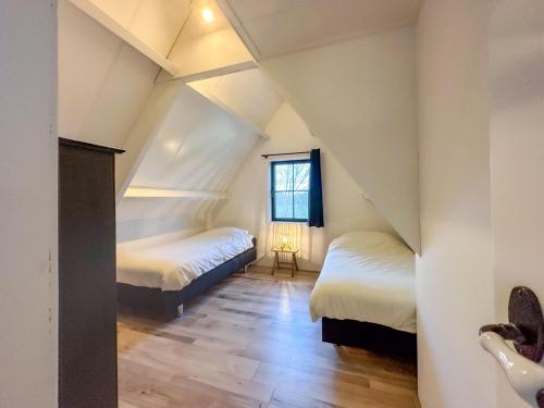 1 dormitorio en el ático con 2 camas y ventana en Dubbel genieten, en Nieuwvliet