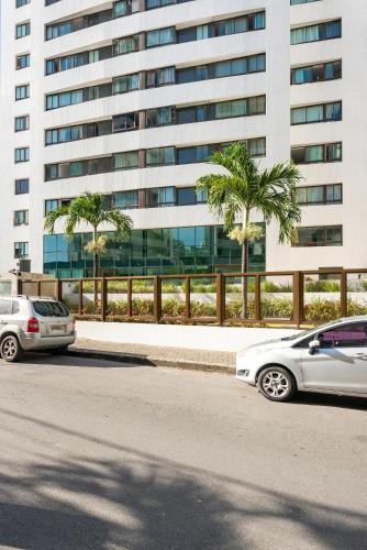 two cars parked in a parking lot in front of a building at Flat 701 - PortoMar Home Club in Recife