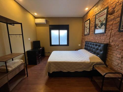 a bedroom with a bed and a brick wall at A CASINA - STUDIOS Metrô FARIA LIMA in Sao Paulo